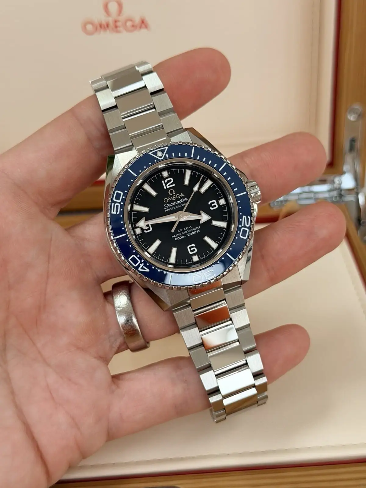 Omega Planet Ocean 42 mm à lunette bleue (2025), avec bracelet Omega et bracelet en caoutchouc.